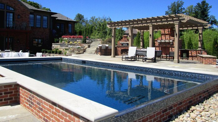 A beautifully designed outdoor space that includes a pool, landscaping, retaining walls and a pergola. 